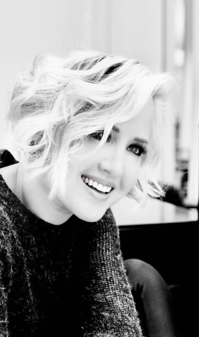 Schwarz-weiß Porträt einer lachenden Frau mit kurzen, lockigen, blonden Haaren