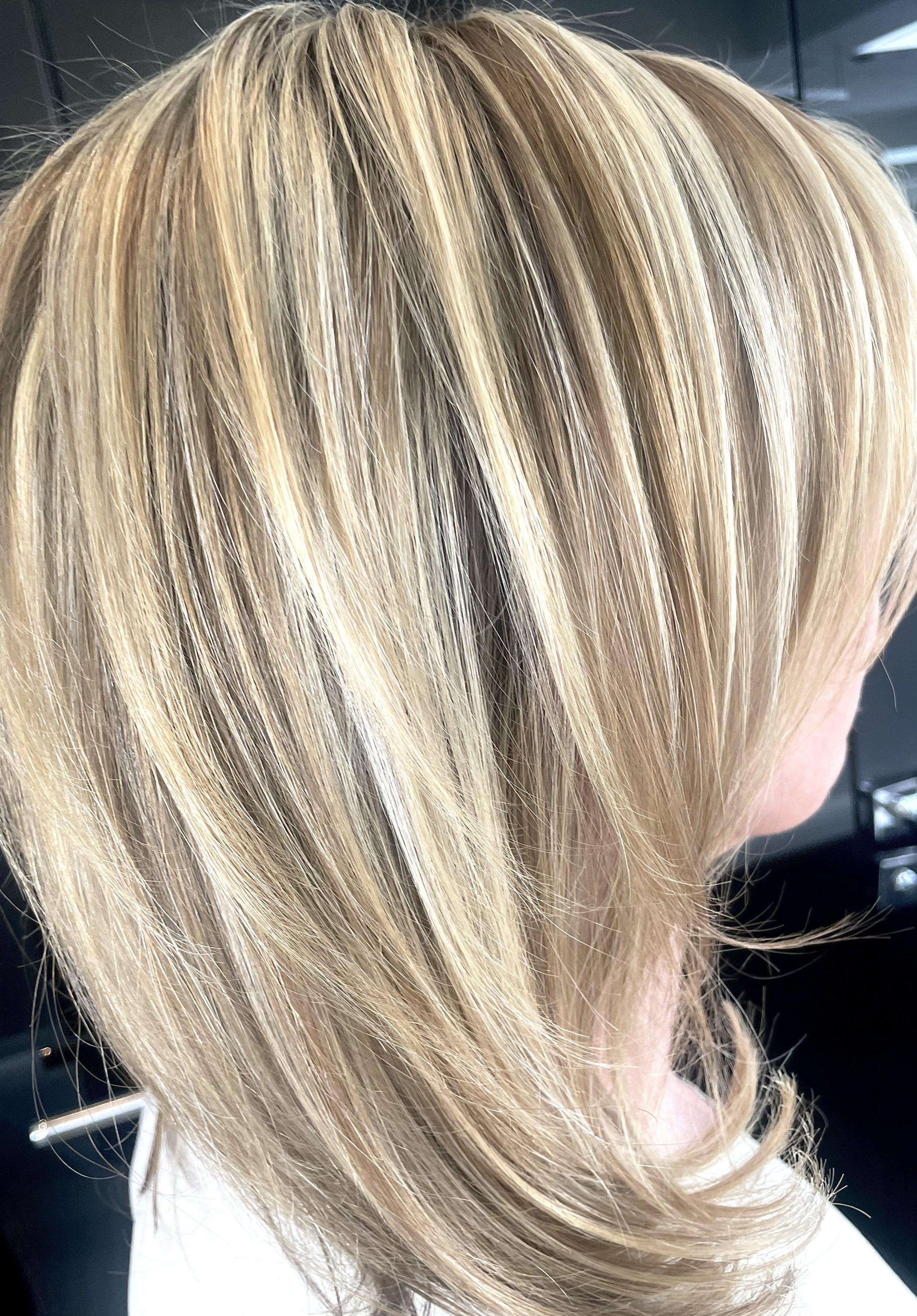 Nahaufnahme einer blonde, gestufte Damenfrisur mit hellen Highlights.